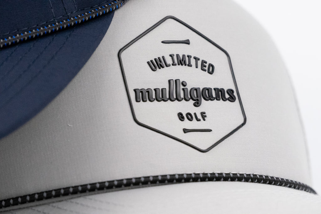 Close-up of a cap with 'Unlimited Mulligans Golf' logo on a white background