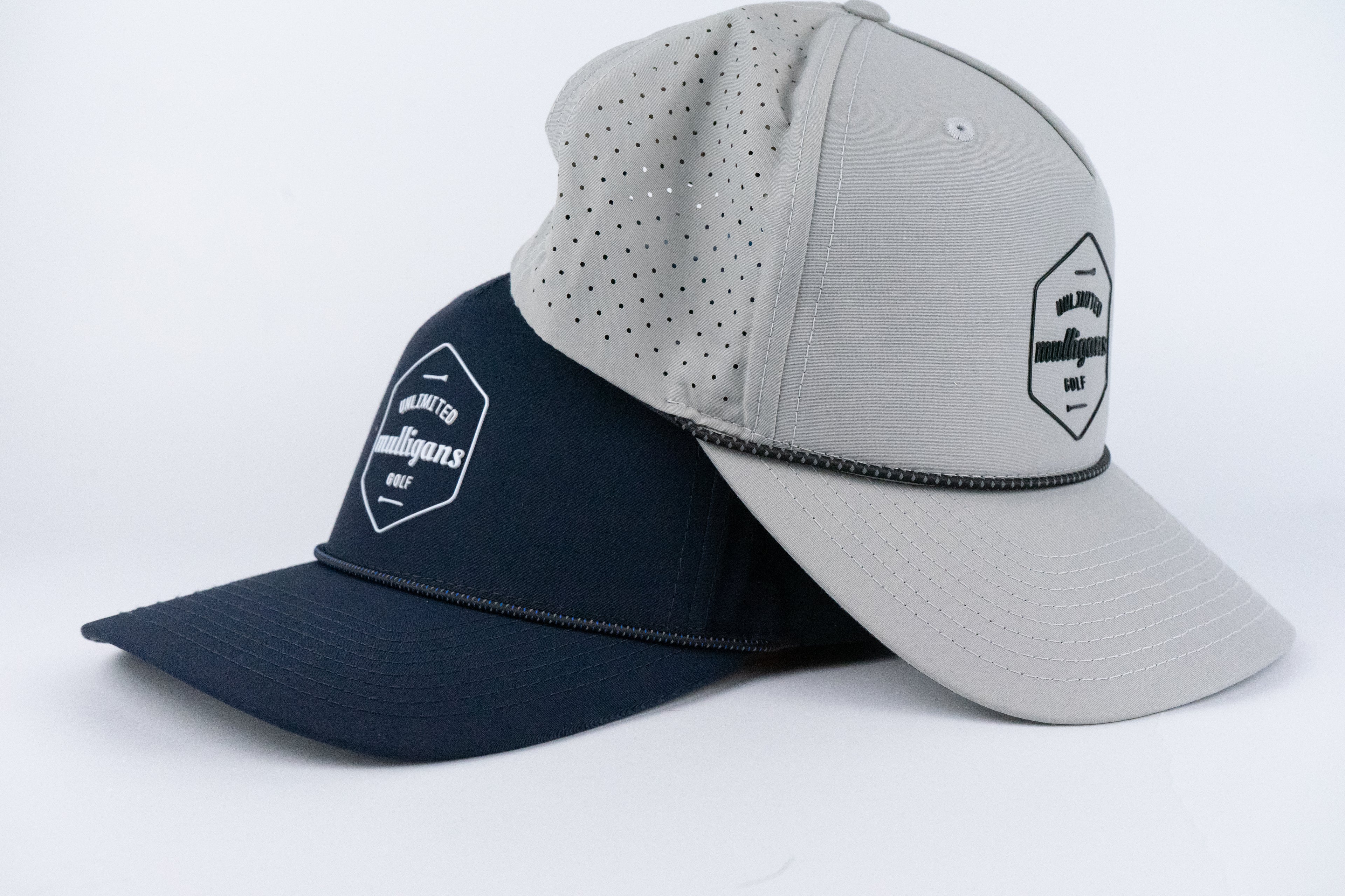 Two rope caps, one navy and one gray, with a visible brand logo for Unlimited Mulligans Golf on a white background.