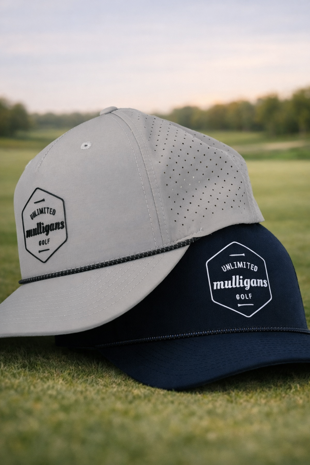 Gray and navy baseball cap with 'Unlimited Mulligan's Golf' logo on a grassy background